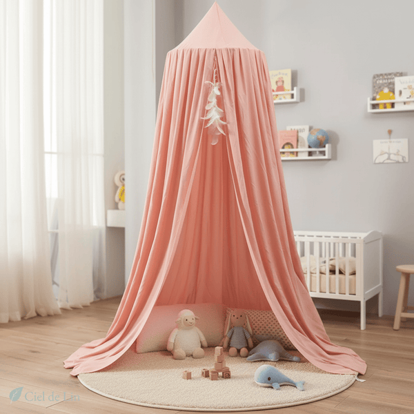 Baldaquin conique bébé rose saumon suspendu au-dessus d’un berceau, chambre douce et aérée