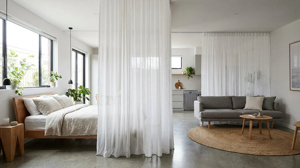 Studio adulte avec ciel de lit voile blanc créant une zone nuit distincte sans cloison