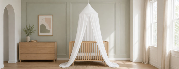 Ciel de lit blanc dans une chambre de bébé aux tons sauge et bois